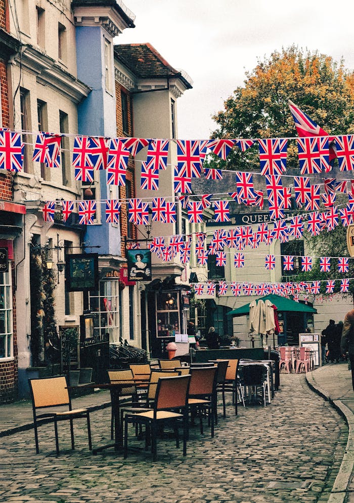 A beautifully decorated British street with Union Jack flags and outdoor seating in a quaint setting.