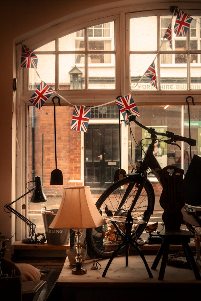 Charming vintage shop window featuring an antique bike and Union Jack flags in Church Stretton, England.